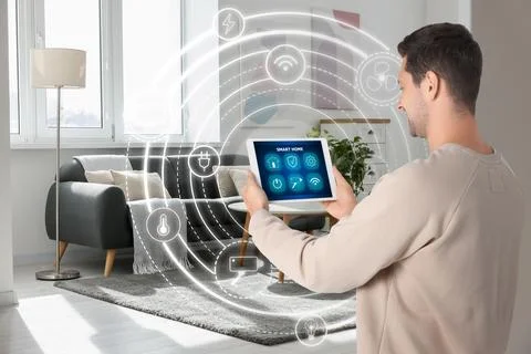 Man using smart home control system via application on tablet indoors. Sche.. Stock Photos