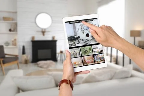 Man using smart home security system on tablet computer indoors, closeup. D.. Stock Photos
