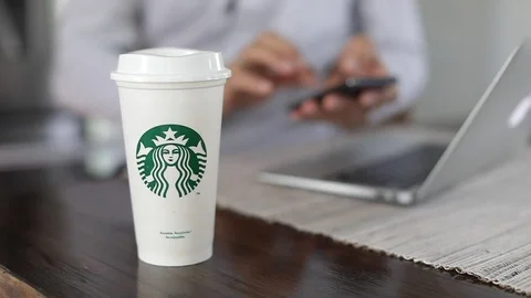 Man using smart phone and drinking Starbucks coffee in home office. Slow Motion. Stock Footage 127796243
