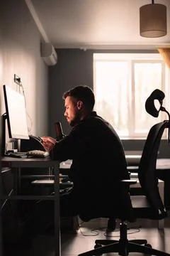 Man using smart phone and computer sitting at desk working at home Foto stock