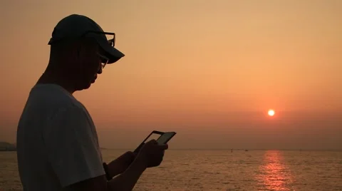 Man using smart phone on beach against beautiful sunset Stock Footage 54316445