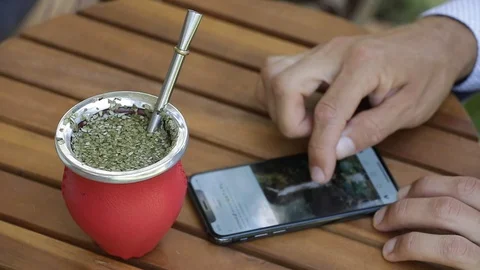 Man using smart phone instagram and drinking yerba mate tea. Slow Motion. Stock Footage 127796631