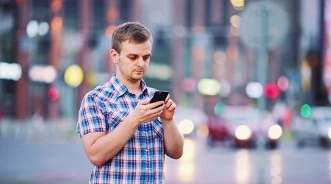 Man using smart phone at night in city. 4K. Busy Street lights background. Vidéo 67847216