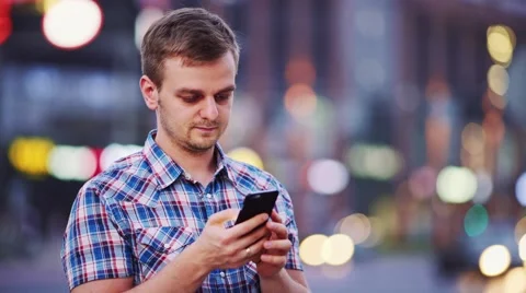 Man using smart phone at night in city. 4K. Busy Street lights background. Видео 67847446