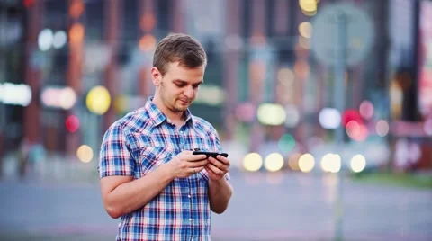 Man using smart phone at night in city. 4K. Busy Street lights background. Stock Footage 67848279