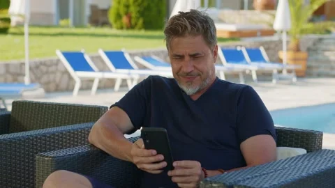 Man using smart phone outdoor on vacation in hotel garden Stock Footage 156080184