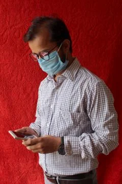 Man using smart phone while wearing surgical mask Stock Photos