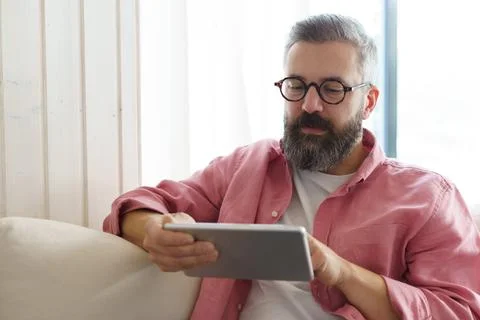 Man using smart thermostat, adjusting, lowering heating temperature at home. Man Stock Photos