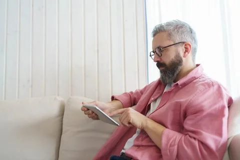 Man using smart thermostat, adjusting, lowering heating temperature at home. Man Stock Photos
