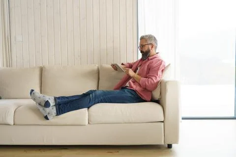 Man using smart thermostat, adjusting, lowering heating temperature at home. Man Stock Photos