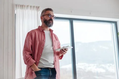 Man using smart thermostat, adjusting, lowering heating temperature at home Stock Photos