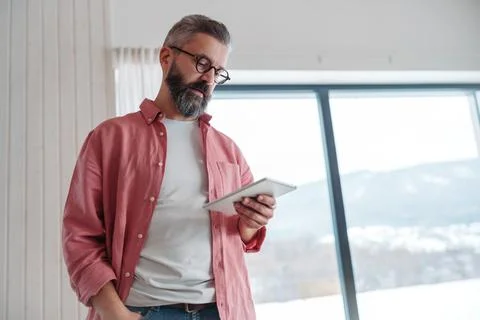 Man using smart thermostat, adjusting, lowering heating temperature at home Stock Photos