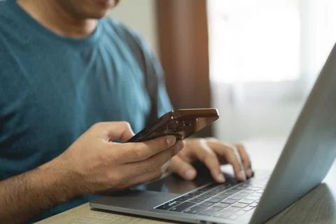 Man using smartphone after working with laptop on table, businessman using mo Stock Photos