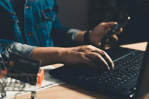 Man using smartphone and computer laptop. which is payment online, sits on .. Stock Photos