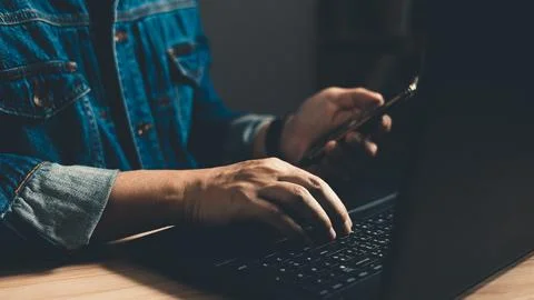 Man using smartphone and computer laptop. which is payment online, sits on .. Stock Photos