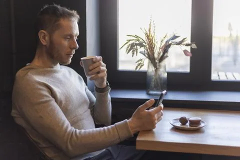 Man Using Smartphone and Drinking Coffee at Cafe Table Profile View Stock Photos