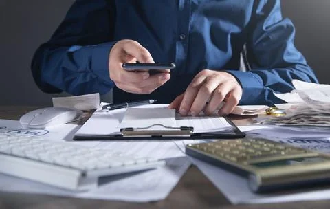 Man using smartphone and holding bills checking for cost. Foto stock