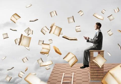 Man using smartphone and many books flying in air Fotos de archivo