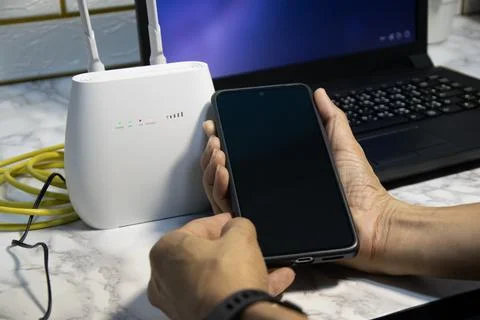 The man is using a smartphone and router, high-speed internet connection, n.. Stock Photos