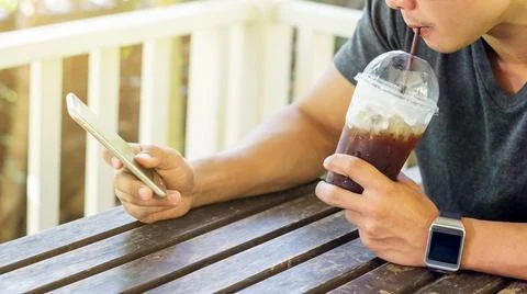 Man using a smartphone and a smartwatch in a coffee shop. Stock Photos