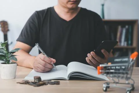 Man using smartphone and taking notes in planning. which is payment online,.. Stock Photos