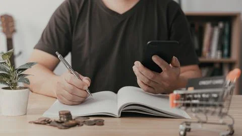 Man using smartphone and taking notes in planning. which is payment online,.. Stock Photos