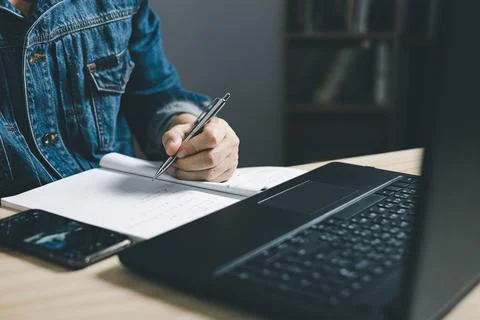Man using smartphone and taking notes in planning. which is payment online,.. Stock Photos