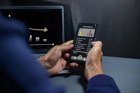 Man using a smartphone app to calculate the monthly bills or household expens Stock Photos