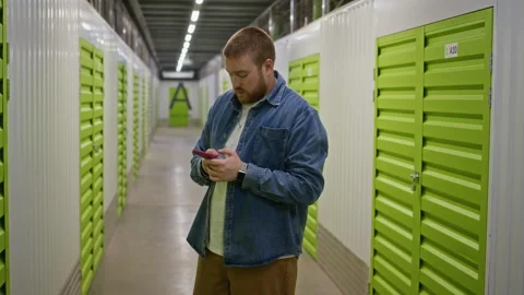 Man Using Smartphone App to Locate Unit in Self Storage Facility Stock Footage 340285501