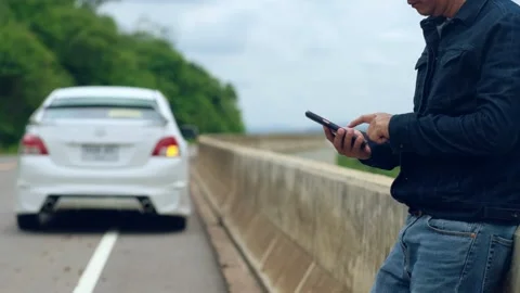 A man is using a smartphone to ask for help as his car is parked Stock Footage 147976060