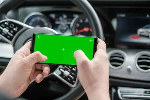 Man using smartphone on the background of a luxury class car dashboard Stock Photos