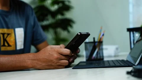 Man using smartphone beside laptop at desk, Man using a smartphone beside a.. Stock Footage 348345995