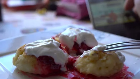 Man using smartphone at breakfast time. Cheese pancakes, minicakes and berry jam Stock Footage 71766988