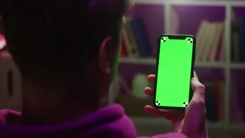 Man using smartphone with chroma key in evening. Young guy sitting on sofa and Stock Footage 167669692
