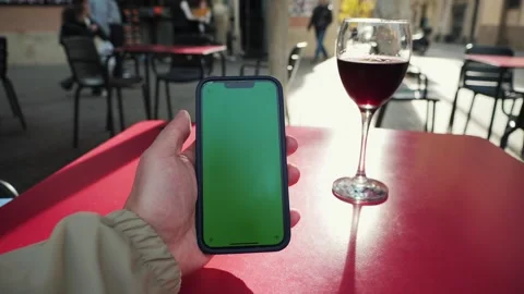 Man using a smartphone with a chroma key green screen and drinking red wine on Stock Footage 318747585
