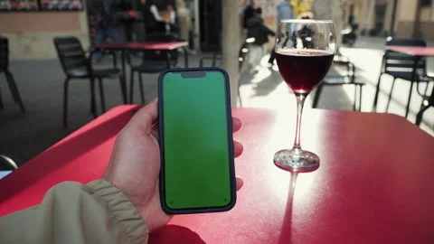 Man using a smartphone with a chroma key green screen and drinking red wine on Video stock 335140801