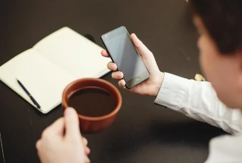 Man using smartphone, close-up, coffee and planning book on the Stock Photos