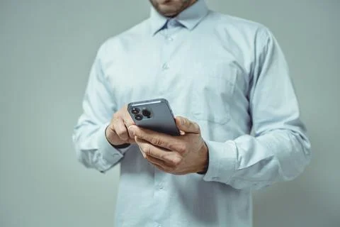 Man using smartphone, close-up.  He's wearing a light blue shirt.  The phon.. Stock Photos