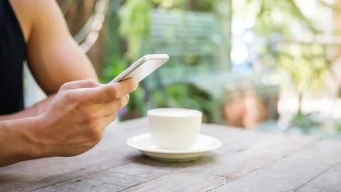 Man using a smartphone in a coffee shop. Stock Photos