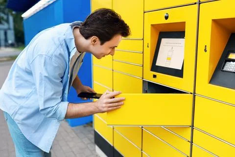 Man using a smartphone for contactless parcel pickup at a yellow self-servi.. Stockfoto's