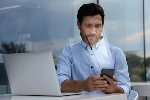 Man using smartphone with facial recognition system in cafe. Security appli.. Stock Photos