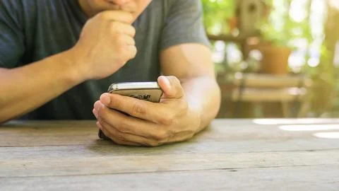 Man using a smartphone in a garden. Stock Photos
