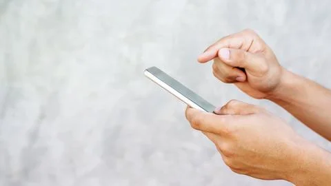 Man using a smartphone on gray background. Stock Photos