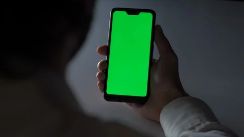 Man using a Smartphone with Green Mock-up Screen in office at night Stock Footage 118763996