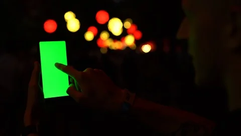 Man using Smartphone with Green Screen chromakey, background of blurred lights Stock Footage 95839083