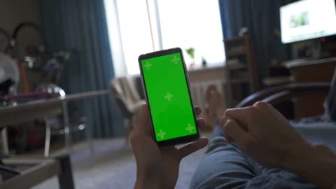 Man using smartphone with green screen at home, watching news Stock Footage 115435283