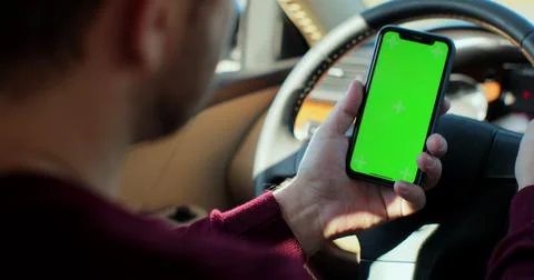 Man using smartphone with green screen chroma key inside car. Concept: direction Photos