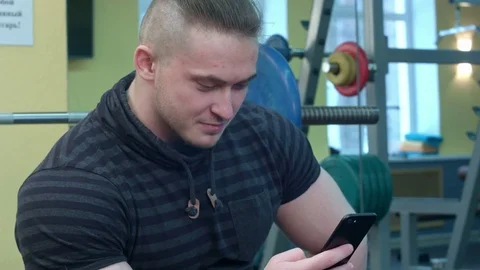 Man using smartphone in the gym after training Видео 73918501