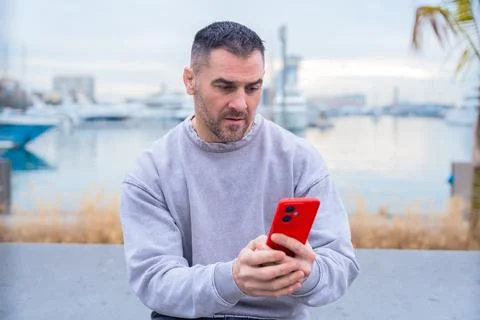 Man Using Smartphone by the Harbor Foto stock