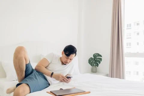 Man is using the smartphone on his bed in concept of relaxation. Stock-Fotos